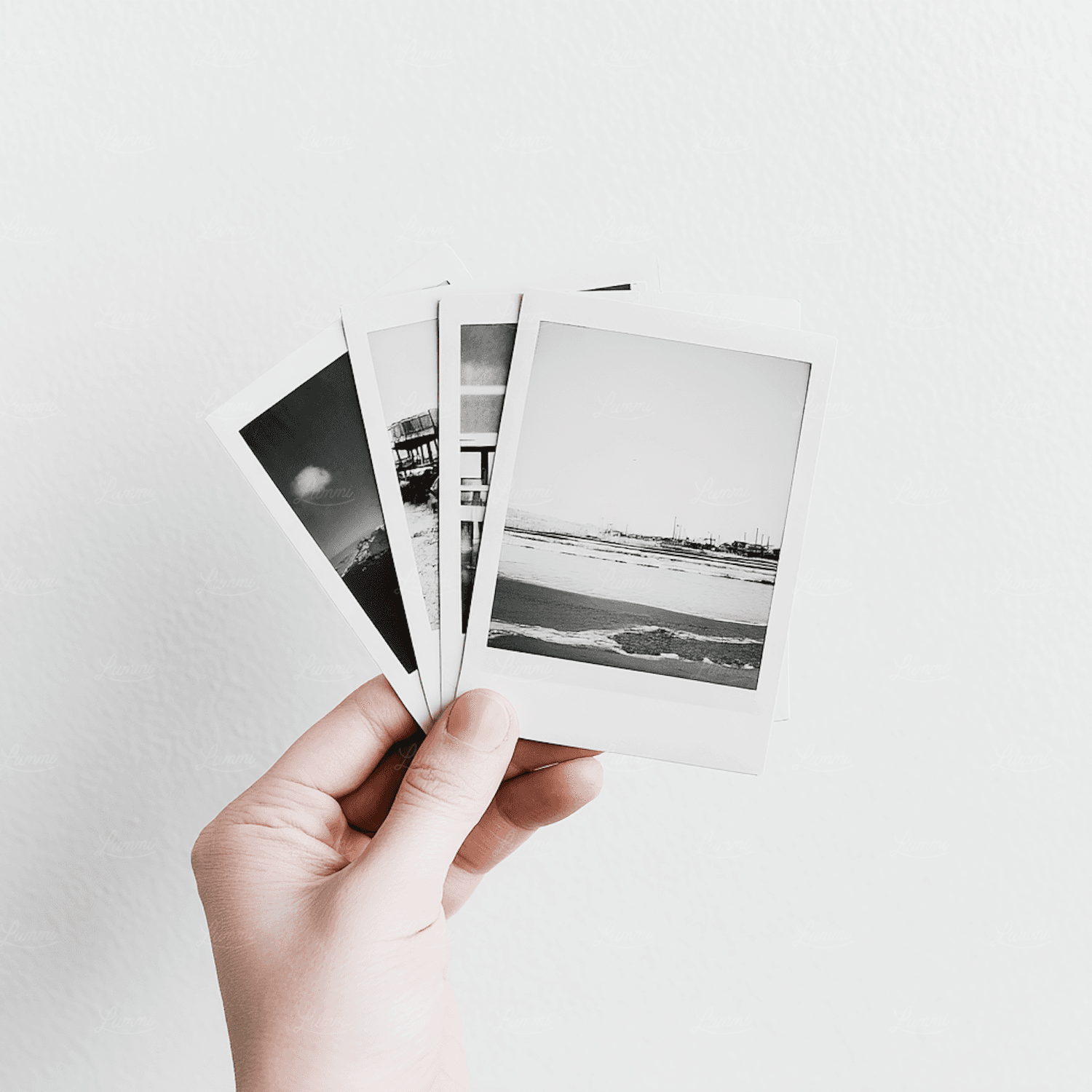 A hand holding a set of small monochrome landscape prints